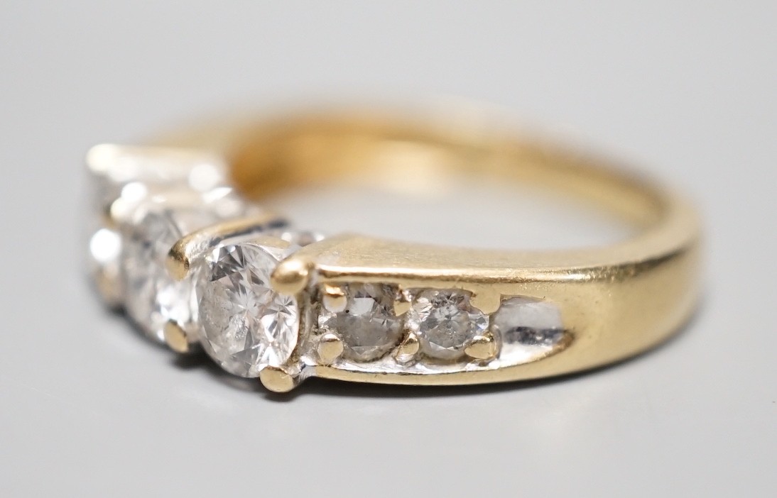 A 14k yellow metal and three stone diamond ring, with four stone diamond set shoulders, size K, gross weight 4.3 grams